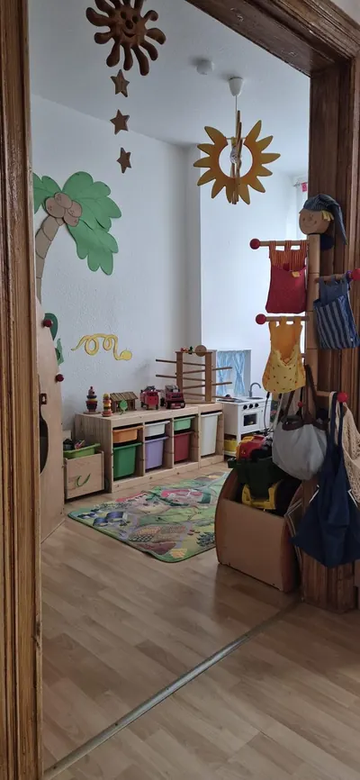 Spielzimmer mit Holzspielzeug, Kinderküche und Spielteppich in der Kindertagespflege